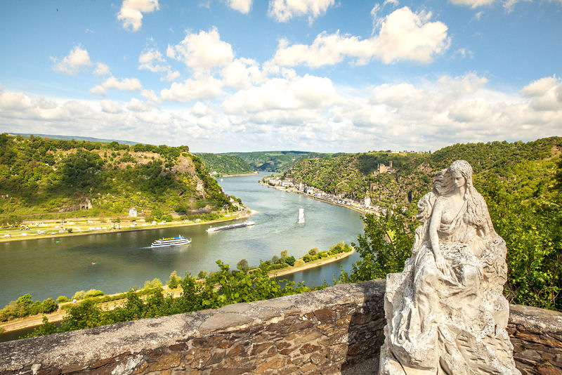 Figur der Lorelei hoch auf dem Felsen am Ufer des Rhein. 